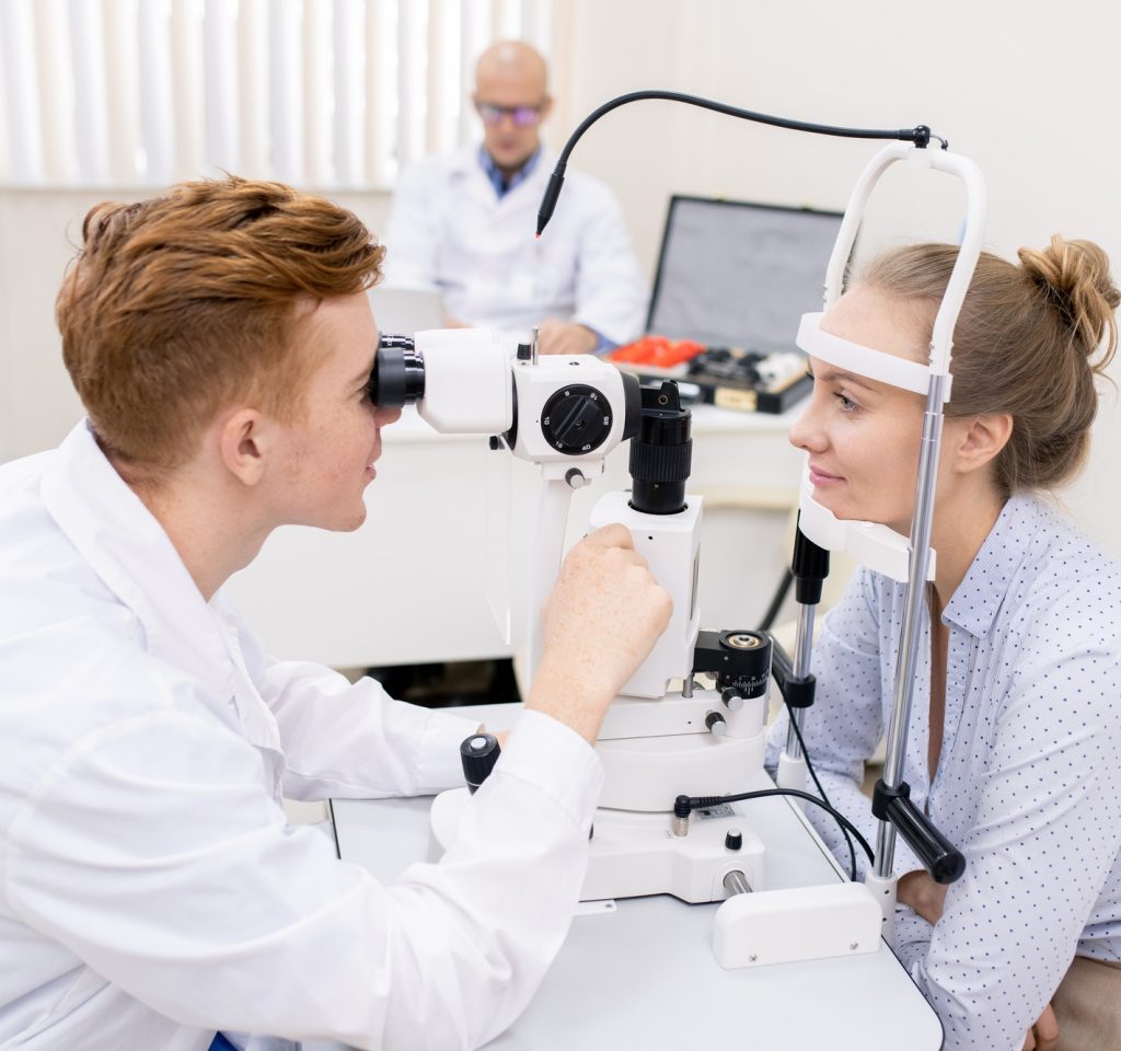 young-optometrist-looking-through-lens-of-eyesight-check-up-equipment